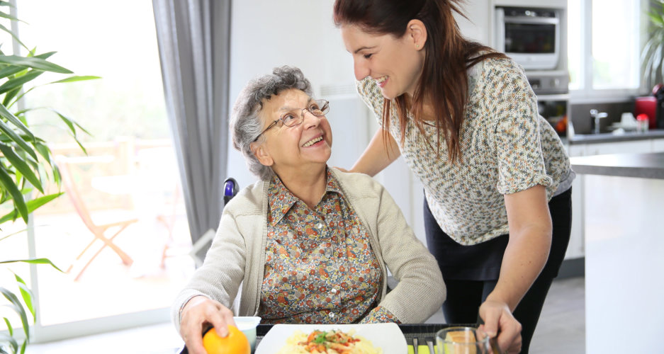 caregiver assisting senior woman in her meal